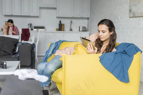 母亲用平板电脑和模糊的女儿在背景 母亲用平板电脑和模糊的女儿在背景