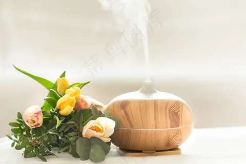 桌上的香油扩散器灯上模糊着一束美丽的郁金香。 桌上的香油扩散器灯上模糊着一束美丽的郁金香。