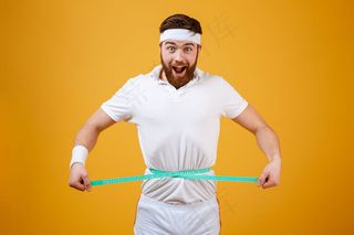 快乐的大胡子健身男子用卷尺量腰围