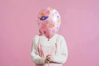 在纯粉色背景中拿着节日气球的女人