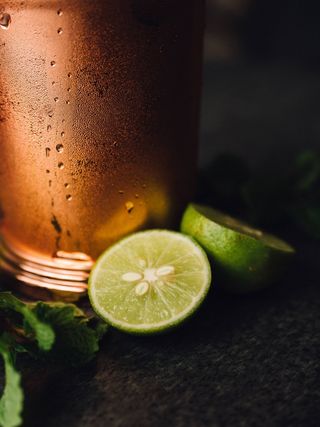 背景模糊的冷铜杯附近的柠檬垂直特写镜头