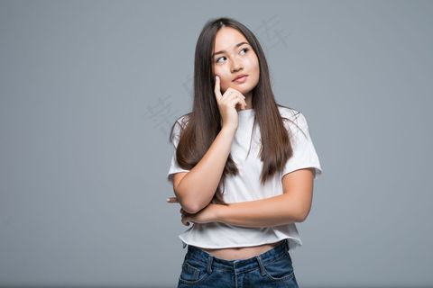 思考的女人和看复制空间孤立在灰色的背景上，手指在脸上，亚洲美人