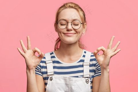满意的金发美女迷人的快乐女性的肖像表示ok标志，闭上眼睛，心情愉快，周末快乐，与粉色隔离