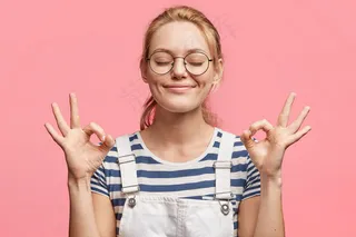 满意的金发美女迷人的快乐女性的肖像表示ok标志，闭上眼睛，心情愉快，周末快乐，与粉色隔离