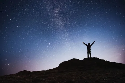 年轻人的剪影银河系背景在明亮的恒星黑暗的天空色调 年轻人的剪影银河系背景在明亮的恒星黑暗的天空色调
