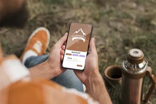 露营时手持智能手机的人的高角度