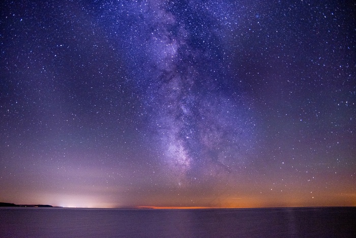 在充满星星的黑暗和紫色天空下拍摄的大海令人叹为观止