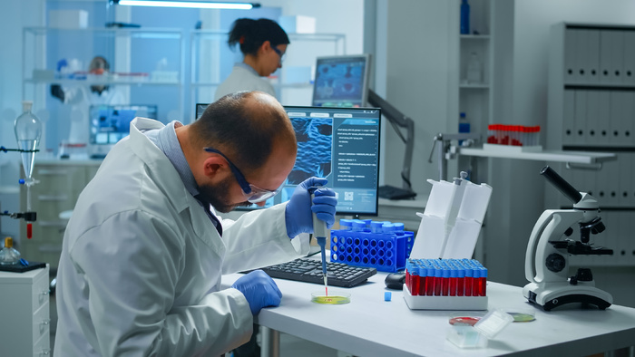 科学家将试管中的血样与微量移液管放入培养皿中分析化学反应