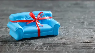 黑色木地板上系着红色礼品带的蓝色沙发。不寻常的礼物。