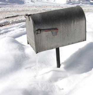 一个银色邮箱的上方拍摄，冬季表面有雪