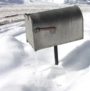 一个银色邮箱的上方拍摄，冬季表面有雪