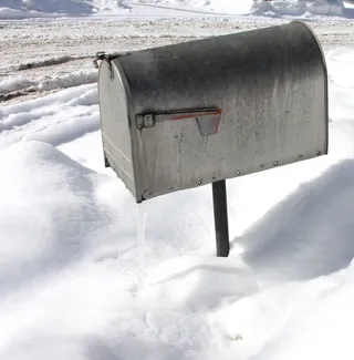 一个银色邮箱的上方拍摄，冬季表面有雪