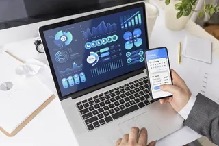 拿着笔记本电脑和电话在办公桌旁工作的人