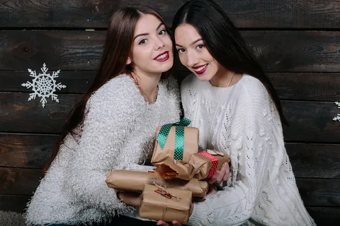 两个年轻漂亮的女人的画像,拿着圣诞礼物 两个年轻漂亮的女人的画像,拿着圣诞礼物