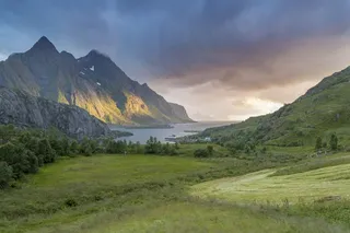 美丽的草覆盖的山谷，湖边有一座雄伟的山