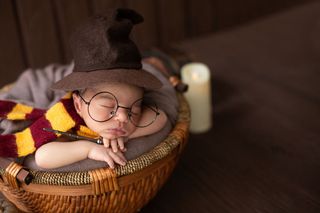 男婴躺在小篮子里，穿着滑稽的巫师服装