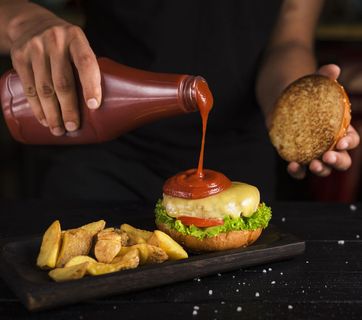 把番茄酱倒在融化的奶酪汉堡上