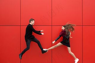 年轻漂亮的情侣在红墙前摆姿势