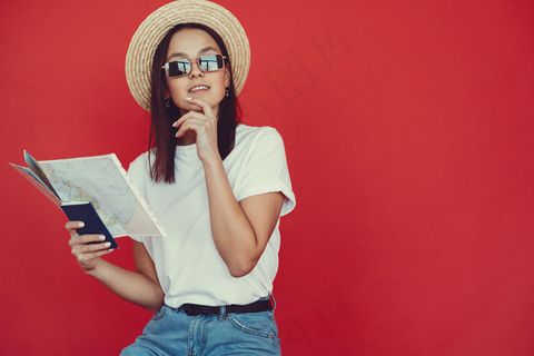 红墙上摆着旅游设备的时髦女孩