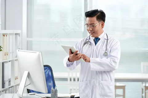 亚洲医生在他的数码设备上使用医疗应用程序 亚洲医生在他的数码设备上使用医疗应用程序
