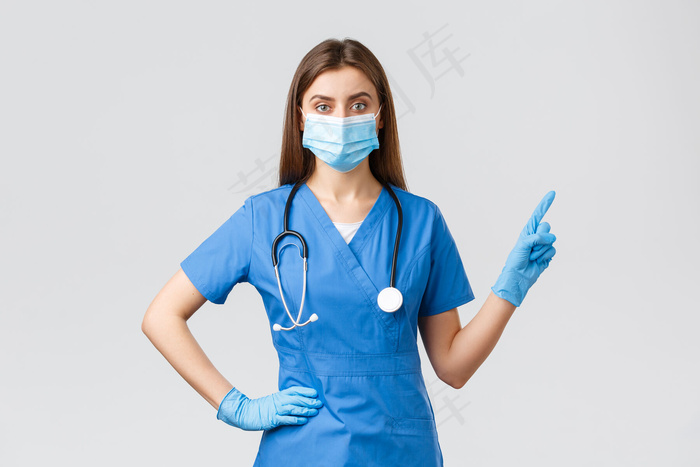 Covid-19，预防病毒，健康，医护人员和检疫概念。自信的女护士穿着蓝色的护甲，戴着医用面罩，指指点点