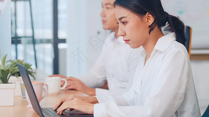 成功的漂亮的亚洲女经理，年轻的女商人，在现代办公室工作的过程中，在笔记本电脑旁观看创意教程。