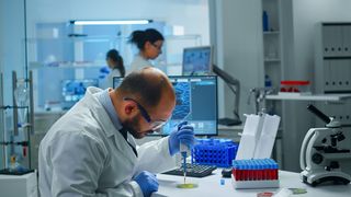 医学实验室科学家研究药物发现，用微量移液器将血样放入培养皿中