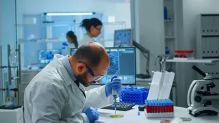 医学实验室科学家研究药物发现，用微量移液器将血样放入培养皿中