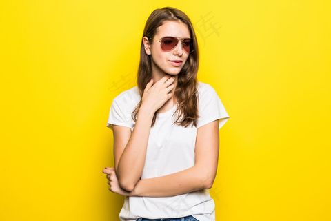 穿着白色t恤和蓝色牛仔裤的年轻女士站在黄色摄影棚前 穿着白色t恤和蓝色牛仔裤的年轻女士站在黄色摄影棚前