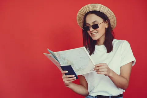 红墙上摆着旅游设备的时髦女孩 红墙上摆着旅游设备的时髦女孩
