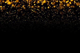 金色闪闪发光的灯光在黑暗的背景下闪烁着抽象的粒子。