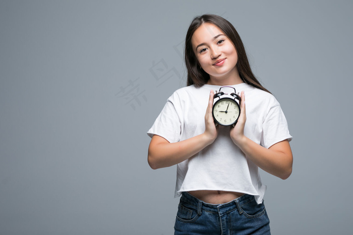 年轻的亚洲女人微笑着，灰色背景上有一个孤立的时钟