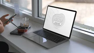 在白色桌子上拿着智能手机和笔记本电脑模型样机的女人的特写镜头