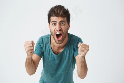 情感与成就观。特写镜头:快乐成功的学生或员工穿着便装尖叫,脸上挂着胜利的表情,挥舞着拳头,在白色的墙上庆祝成功 情感与成就观。特写镜头:快乐成功的学生或员工穿着便装尖叫,脸上挂着胜利的表情,挥舞着拳头,在白色的墙上庆祝成功