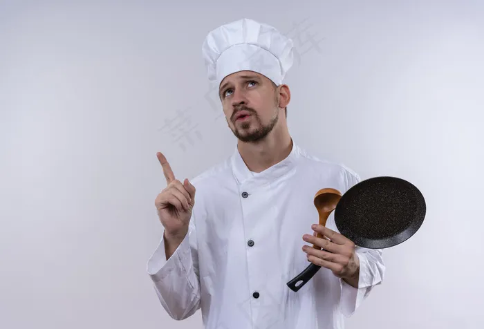 职业男厨师长，身穿白色制服，头戴厨师帽，手持煎锅和木勺，站在白色背景上，用手指向上看，表情沉思
