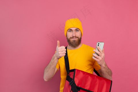 快乐的欧洲送货员，带着小包，随意拿着粉红色的电话