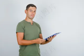 穿着军绿色t恤拿着剪贴板的年轻人，正视图。