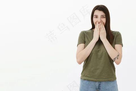 哦，天哪，里面有什么。惊讶和兴奋年轻迷人的女孩纹身微笑手在嘴唇上从惊喜的礼物笑着与眼睛兴奋和喜悦越过灰色的墙壁