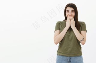 哦，天哪，里面有什么。惊讶和兴奋年轻迷人的女孩纹身微笑手在嘴唇上从惊喜的礼物笑着与眼睛兴奋和喜悦越过灰色的墙壁