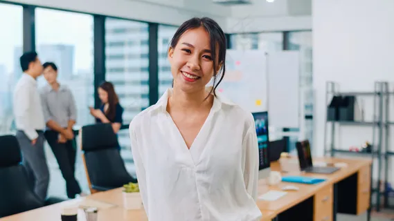 在现代办公场所,一位成功的漂亮的女商务人士在照相机前微笑。站在当代会议室的年轻亚洲女士。 在现代办公场所,一位成功的漂亮的女商务人士在照相机前微笑。站在当代会议室的年轻亚洲女士。