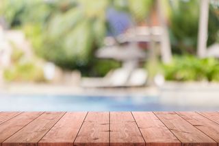 在热带度假胜地的背景下，空木头桌面和模糊的游泳池。