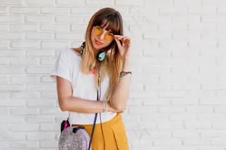 带着耳机在白砖墙上微笑的女人