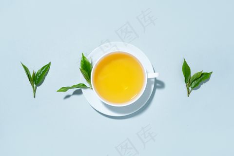 在蓝色粉彩背景上用茶叶泡成的绿茶。俯视图。