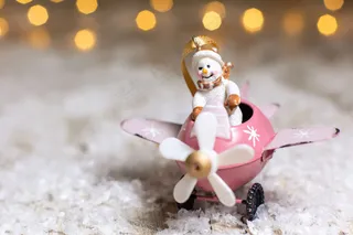 雪人在一架粉红色的飞机上，螺旋桨装饰着节日的气氛，温暖的波基灯。