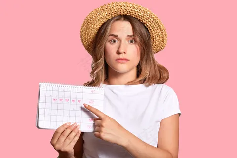 容貌迷人的女子，手持经期历查月经日数，用食指指指点