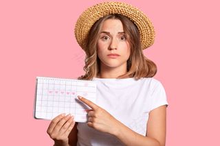 容貌迷人的女子，手持经期历查月经日数，用食指指指点