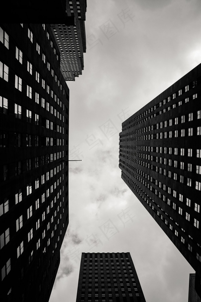背景为多云天空的城市建筑物的垂直低角度灰度