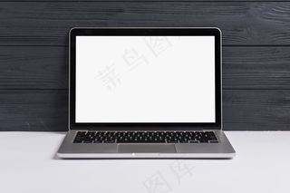 一台打开的笔记本电脑，白色桌面上有一个黑色的木质背景