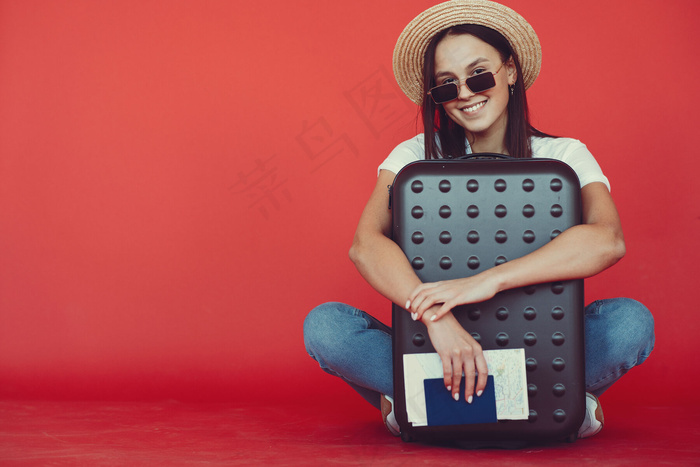 红墙上摆着旅游设备的时髦女孩