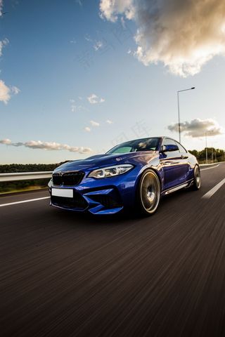 一辆蓝色运动轿车在路上试驾。